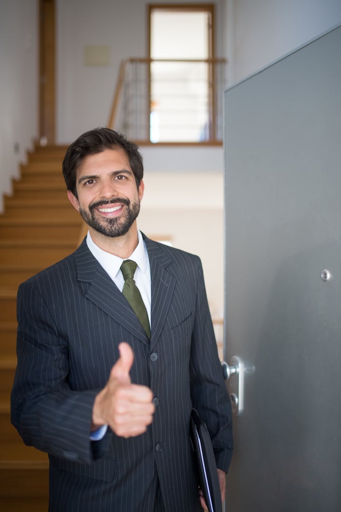 contact-img Smiling realtor giving thumbs up at open house indoors. Ideal for real estate marketing.